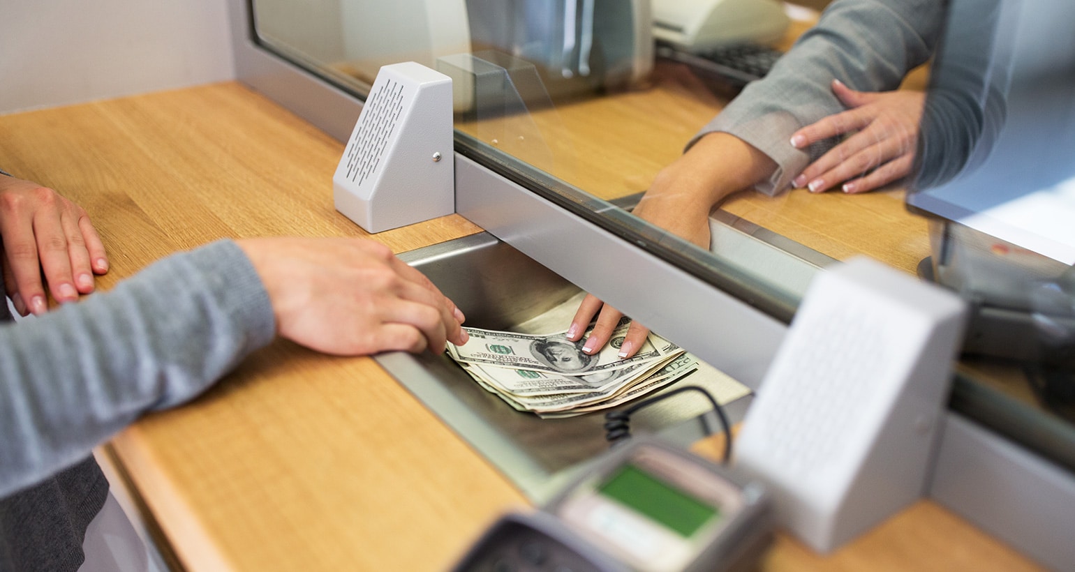 A person receieves cash from a bank teller.