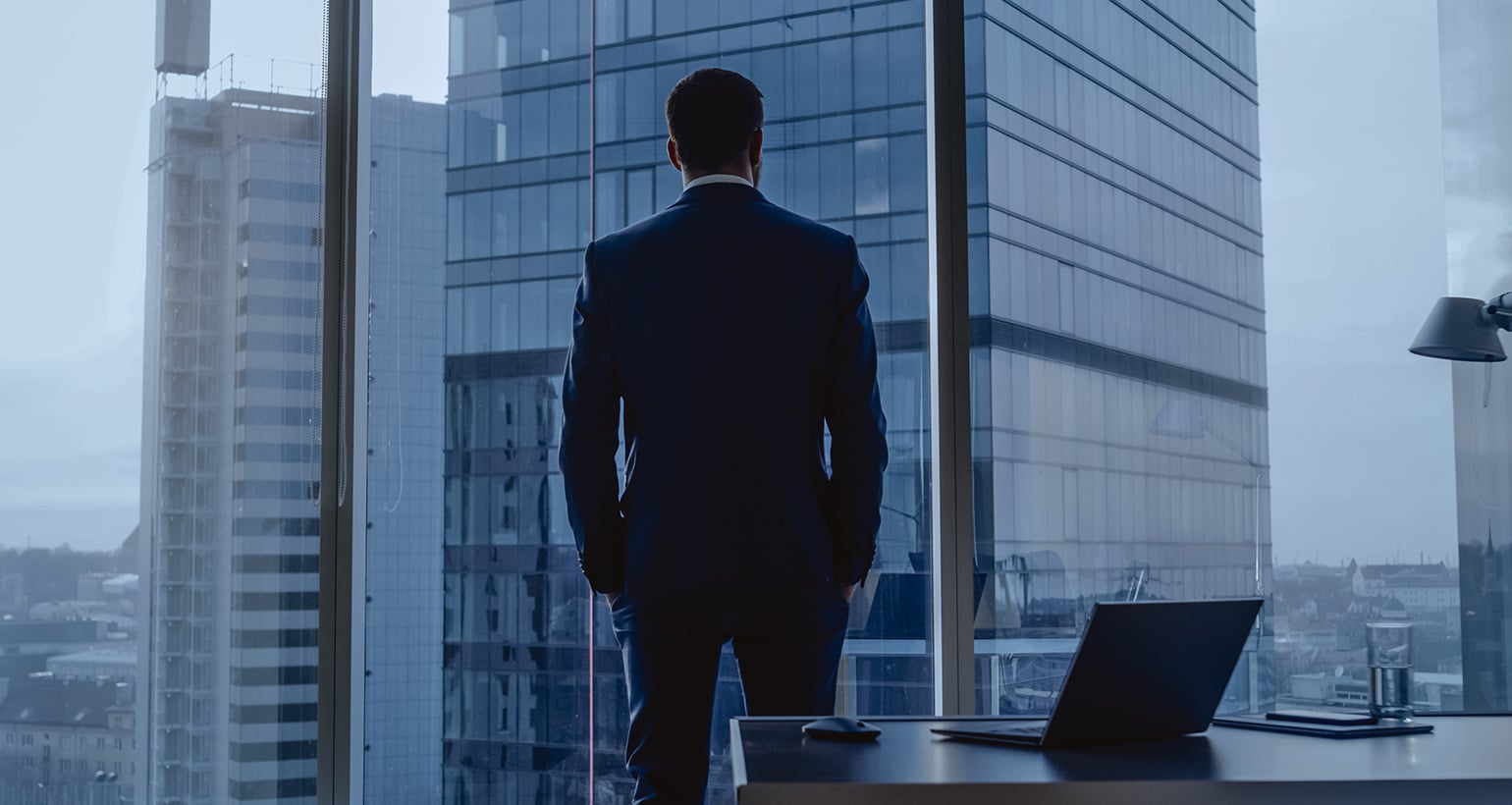 An executive overlooks a city skyline from his office.