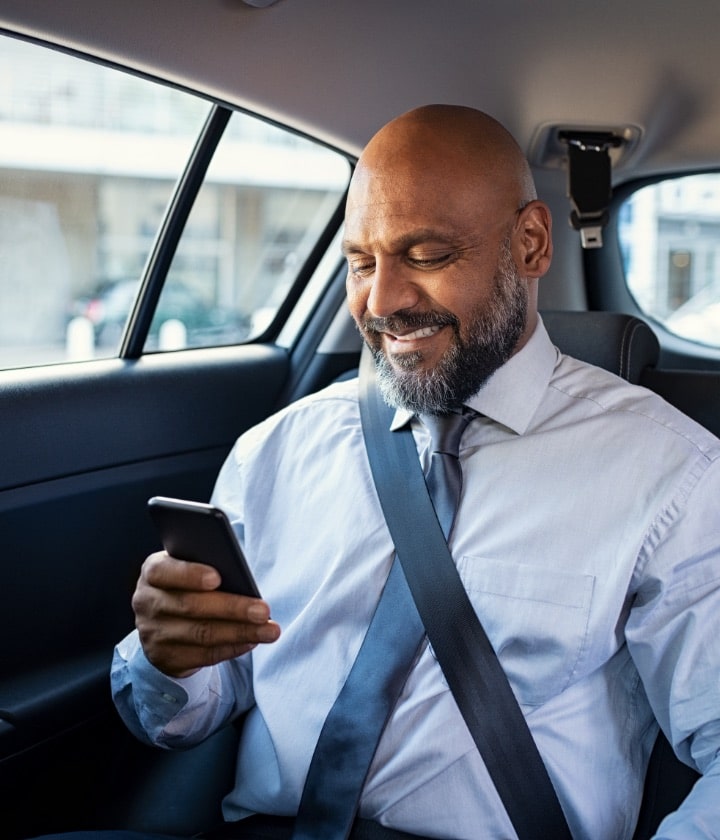 A businessman looks at his personal device while in an Uber.