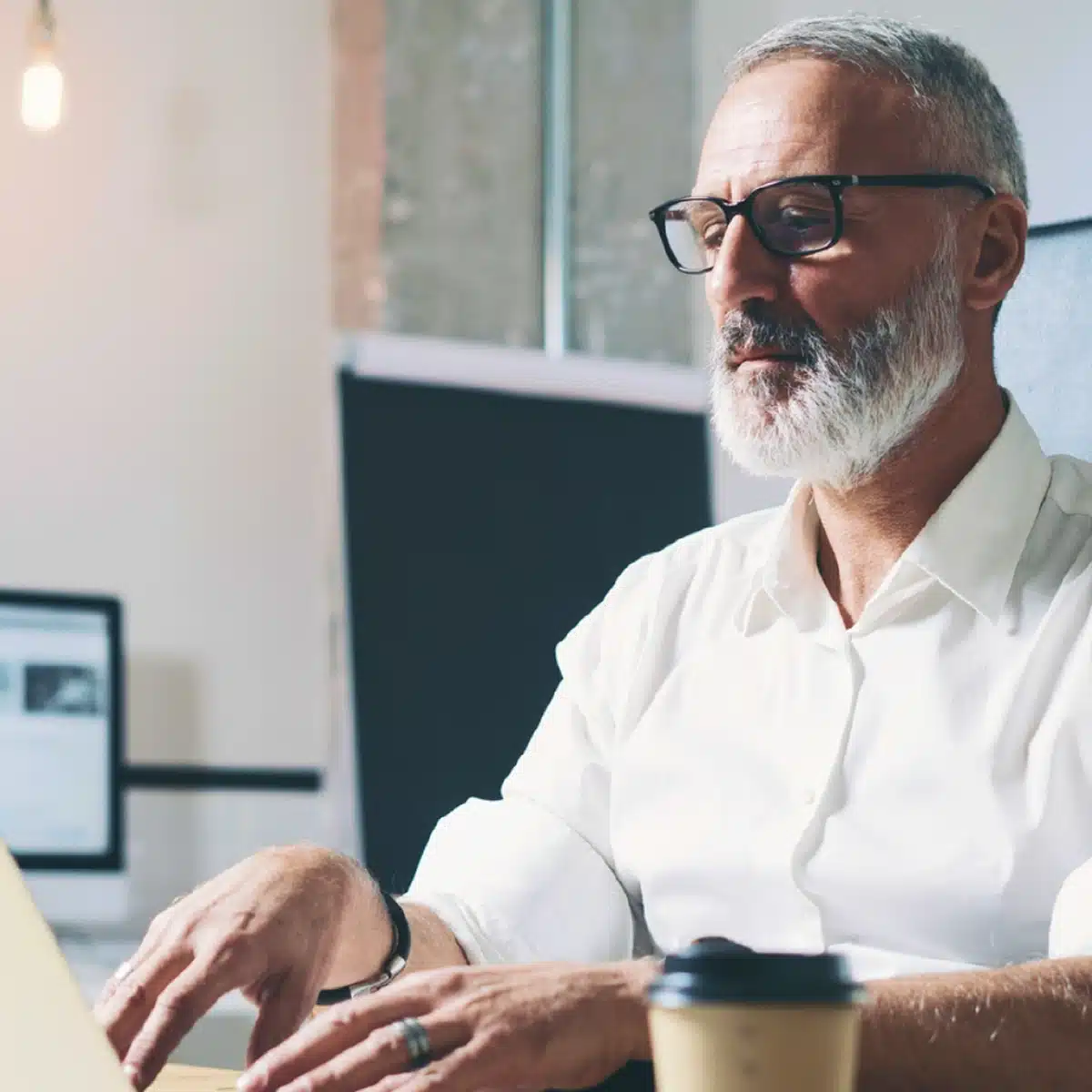 A Chief Information Security Officer (CISO) working on a laptop in a modern office setting.