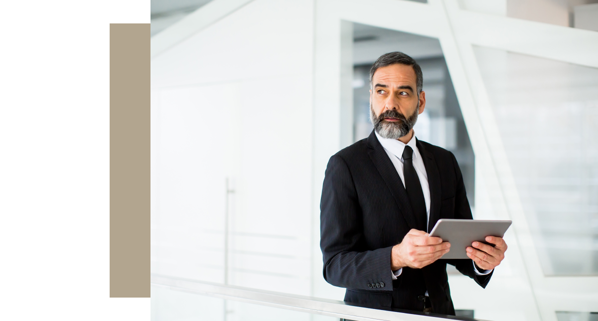 Executive in a suit holding a tablet, representing the need for identity theft protection for business leaders.