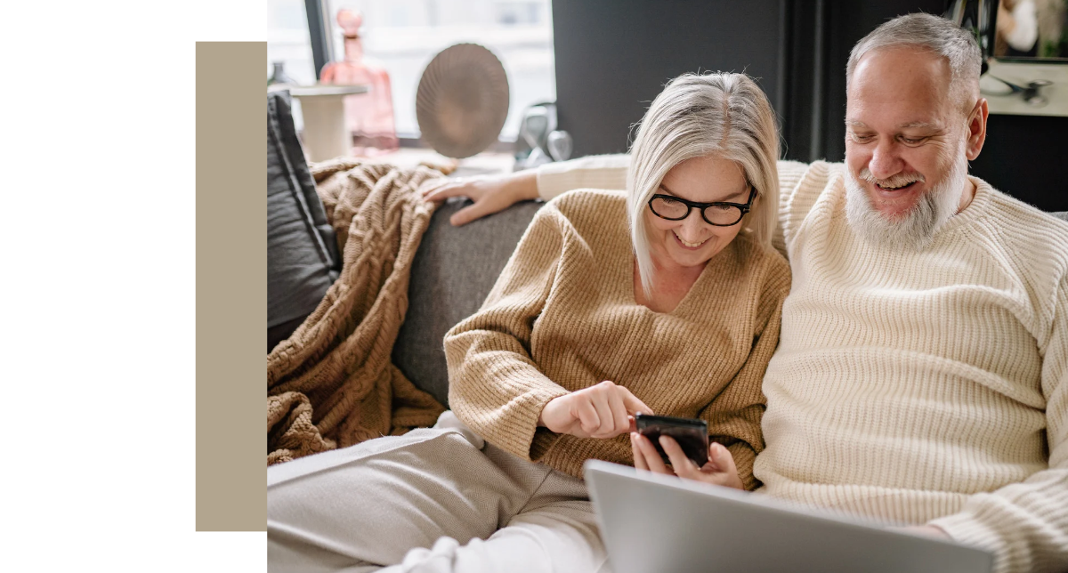 An older couple on a sofa looking at a smartphone together